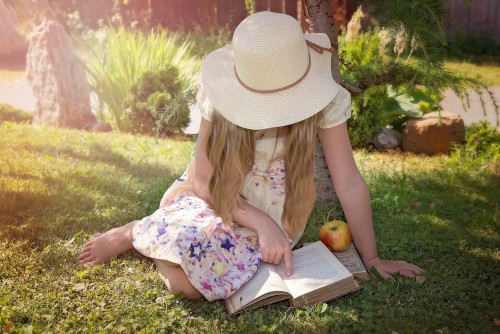 Wunderschöne Kinderbücher Mädchen liest ein Buch im Gras